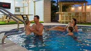 Zona de piscina con un porche cubierto y una pantalla de televisión que muestra 'NETFLIX'.