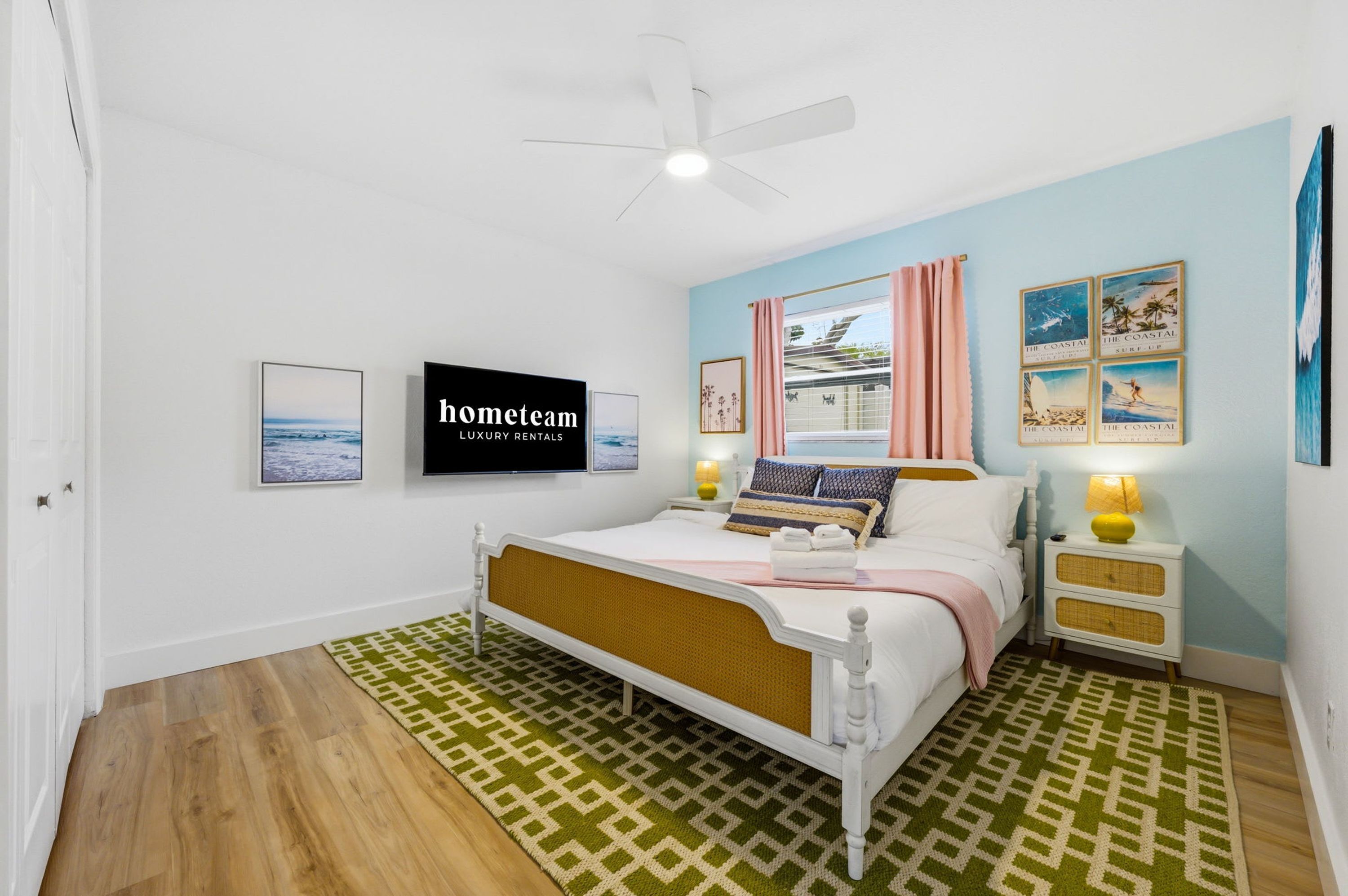 A bedroom with a bed, a television, a ceiling fan, and a window with curtains.