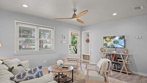 A living room with a ceiling fan, a bookshelf, a coffee table, and a couch. - The Sandpiper Private Deck Bay Boat Parking (Port Aransas)