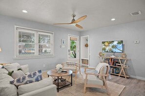 Ein Wohnzimmer mit Deckenventilator, Bücherregal, Couchtisch und Sofa.