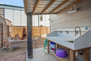 A small outdoor kitchen area with a sink, a hose, and a purple container. - The Sandpiper Private Deck Bay Boat Parking (Port Aransas)