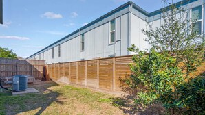 A residential building with a fenced backyard, a wooden deck, and a small tree. - The Sandpiper Private Deck Bay Boat Parking (Port Aransas)