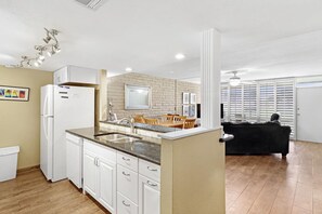 Eine moderne Küche mit weißen Schränken, einer eingebauten Kochinsel mit Spüle und einem Essbereich mit Tisch und Stühlen.