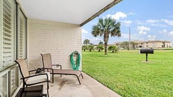 A covered outdoor area with a concrete floor, two chairs, a hose, and a mailbox.