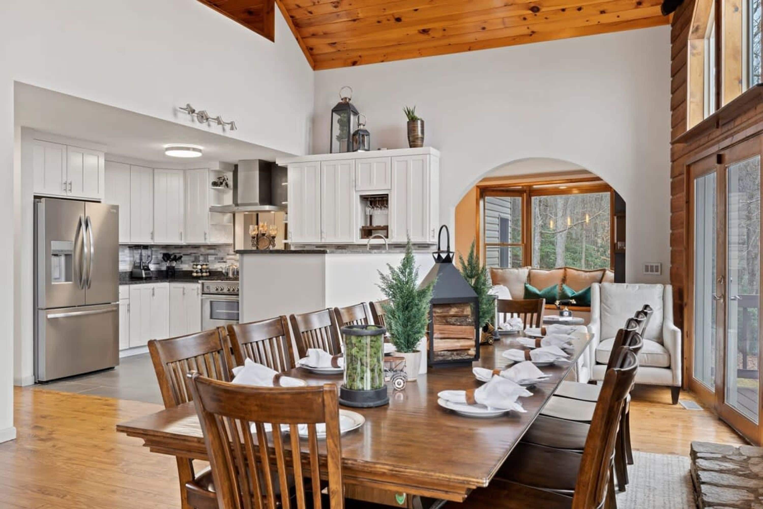 A modern kitchen with white cabinetry, a stainless steel refrigerator, and a dining area with a wooden table and chairs.