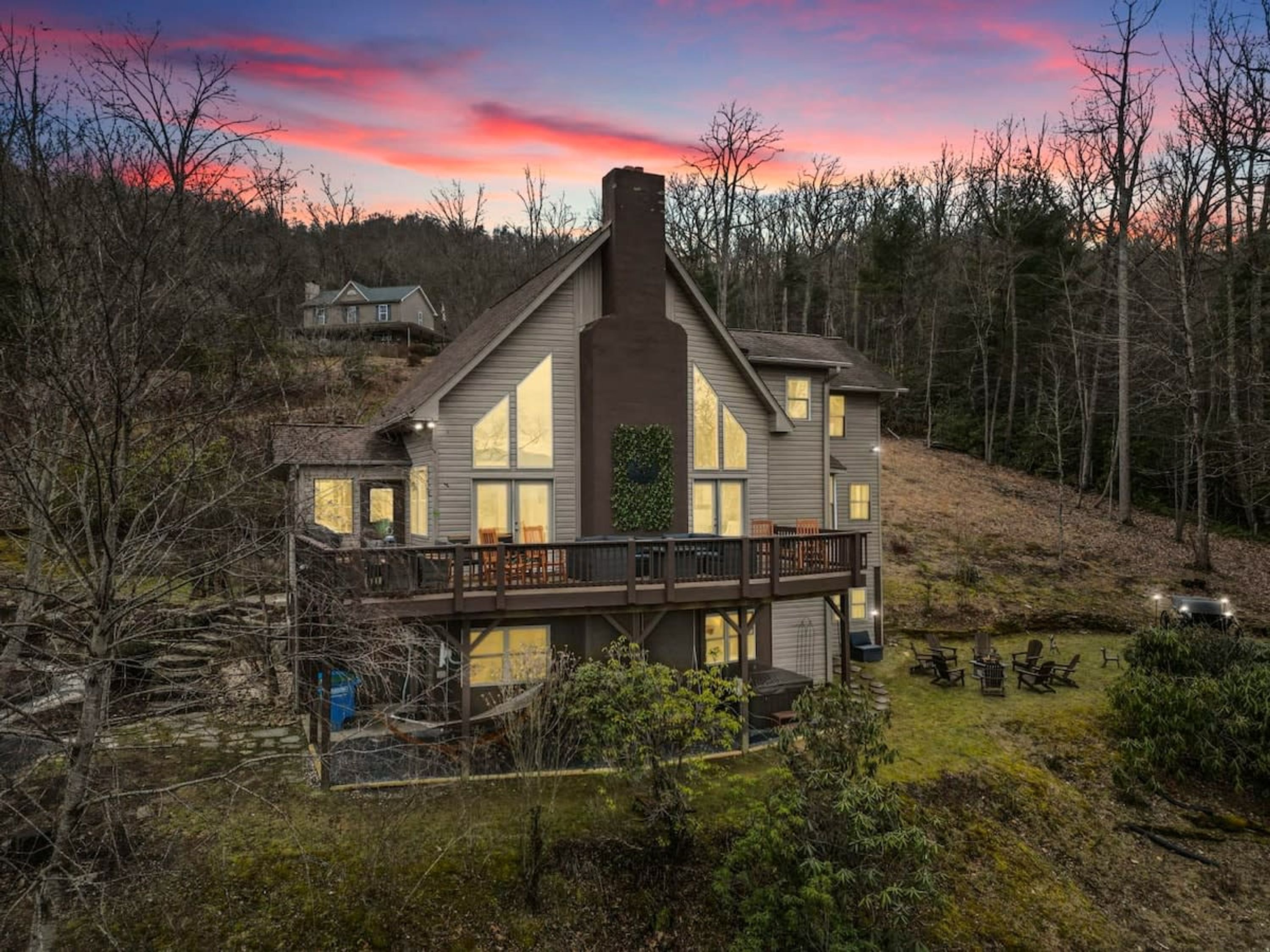 A two-story house with a balcony, surrounded by trees and a grassy yard.