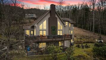 A two-story house with a balcony, surrounded by trees and a grassy yard.