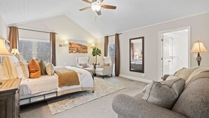 A spacious bedroom with a bed, a sofa, a chair, a ceiling fan, and a large window. - 6 Br Sleeps 16 - Game Room - Hot Tub - Firepit (Fairview)