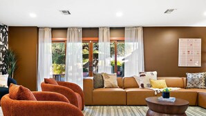 Ein modernes Wohnzimmer mit einem braunen Sofa, orangefarbenen Sesseln und einem Couchtisch.