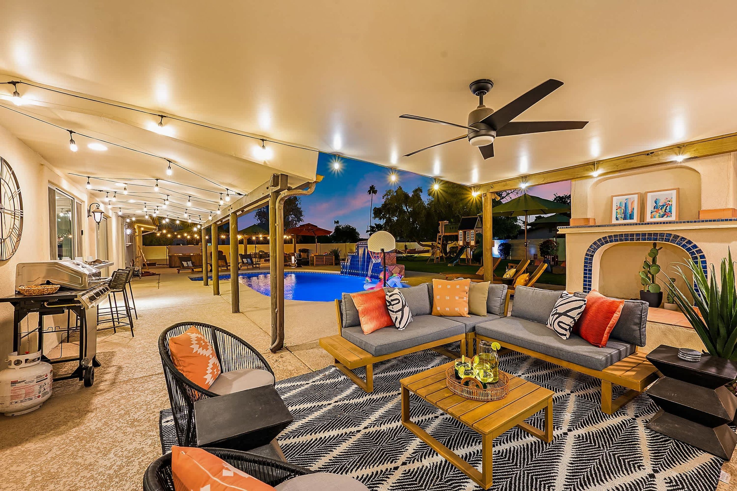 A spacious indoor area with a pool, seating arrangements, and a ceiling fan.