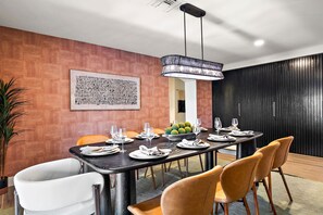 Un'area pranzo moderna con un tavolo lungo, sedie e una lampada a sospensione.