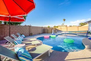 A swimming pool with lounge chairs and inflatable rings, surrounded by a brick wall and a clear sky. - The Brightside Heated Pool Bball Court Bocce (Glendale)