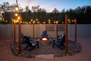 An outdoor seating area with two Adirondack chairs, a fire pit, and string lights. - Private Pickleball Court Movie Room Hot Tub (Scottsdale)