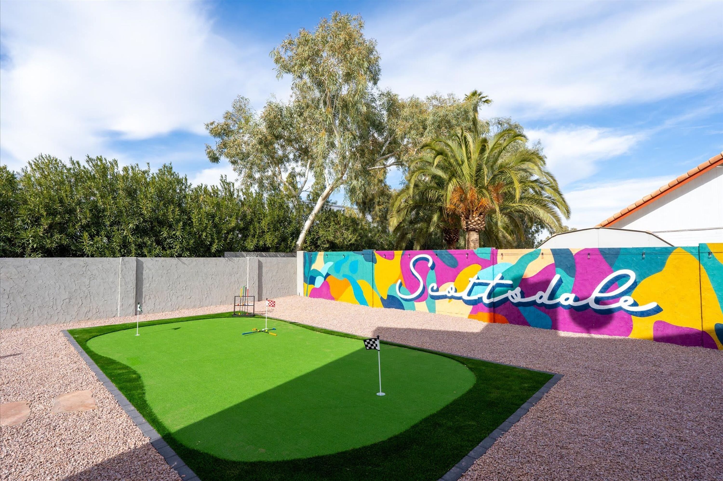 A golf course with a colorful mural, a flagstick, and a well-maintained green.