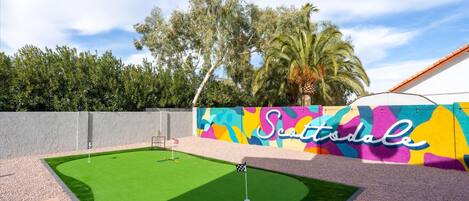 A golf course with a colorful mural, a flagstick, and a well-maintained green.