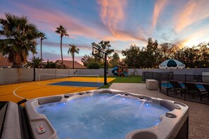 Ein Whirlpool mit Bedienfeld, ein Basketballplatz, eine Rutsche und ein Poolbereich mit Liegestühlen.