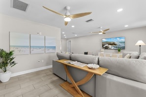 Un salon moderne avec un canapé gris, une table basse en bois et des ventilateurs de plafond.