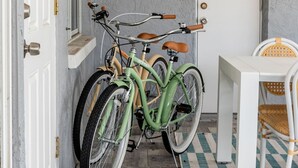A room with a checkered floor, a white door, and two bicycles parked against the wall. - Your Beach Getaway Putt Putt Bikes Game Room BBQ (Largo)