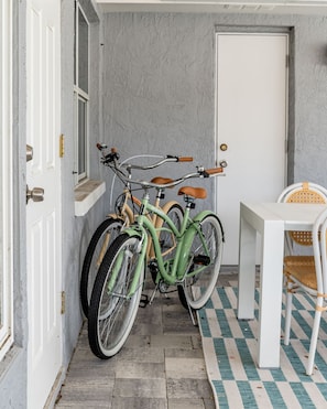 A room with a checkered floor, a white door, and two bicycles parked against the wall. - Your Beach Getaway Putt Putt Bikes Game Room BBQ (Largo)