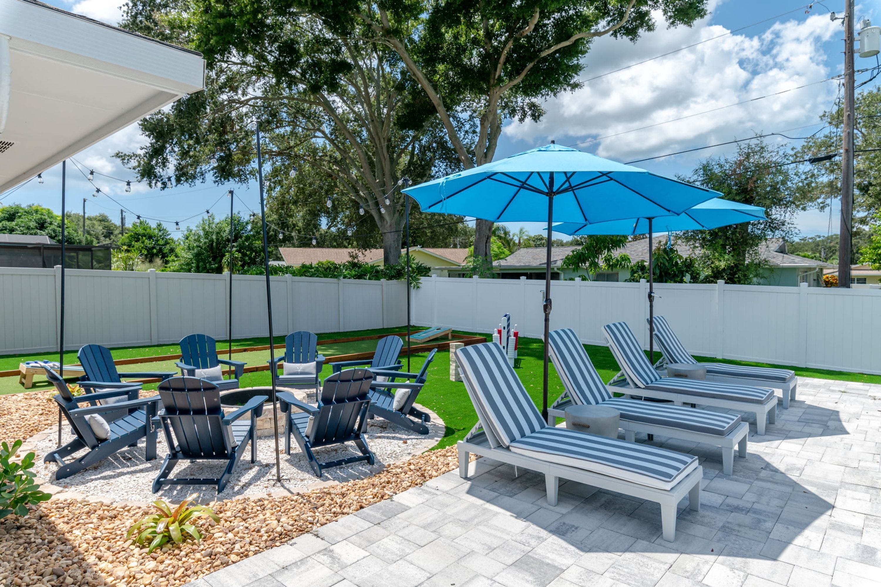 An outdoor patio with lounge chairs and a blue umbrella.