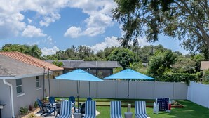 A swimming pool with a tiled deck, lounge chairs, and umbrellas. - Your Beach Getaway Putt Putt Bikes Game Room BBQ (Largo)