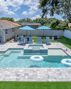A swimming pool with a tiled deck, lounge chairs, and umbrellas. - Your Beach Getaway Putt Putt Bikes Game Room BBQ (Largo)