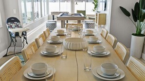 A dining area with a long table set for a meal, surrounded by chairs. - Your Beach Getaway Putt Putt Bikes Game Room BBQ (Largo)