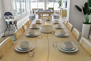A dining area with a long table set for a meal, surrounded by chairs. - Your Beach Getaway Putt Putt Bikes Game Room BBQ (Largo)