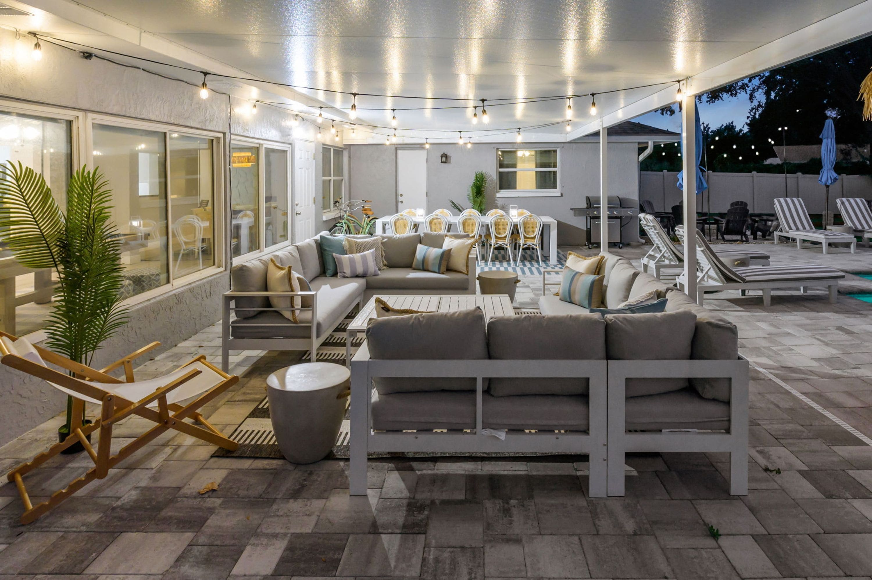 An outdoor patio area with a sofa, chairs, a dining table, and a grill.