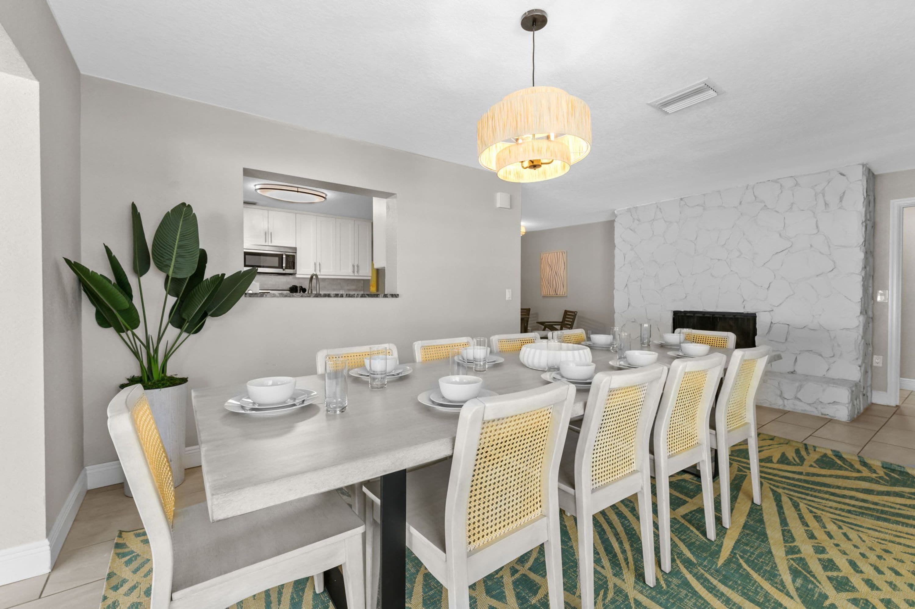 A modern dining area with a white table set for six, surrounded by white chairs with yellow accents.