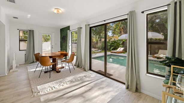 A spacious room with a dining area, a large sliding glass door leading to a pool, and a view of the outdoors. - 1 Mile to Beach Private Pool Oasis Volleyball (Palm Harbor)