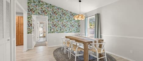 A dining area with a wooden table and chairs, a patterned wall, and a hanging light fixture.