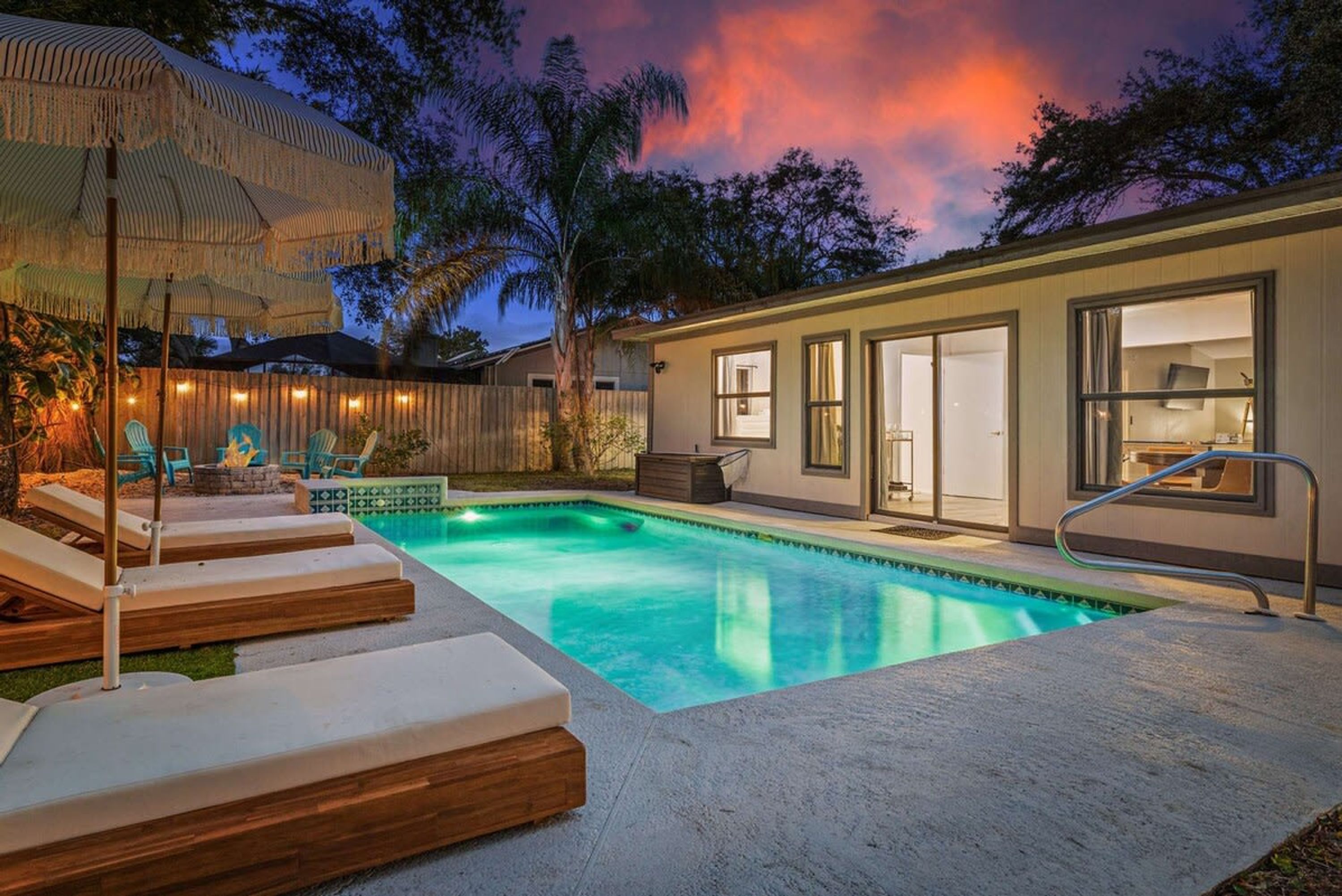 A swimming pool with lounge chairs and a covered seating area.