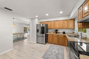 A modern kitchen with wooden cabinets, stainless steel appliances, and a granite countertop. - 1 Mile to Beach Private Pool Oasis Volleyball (Palm Harbor)