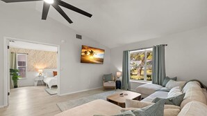 A modern living room with a sofa, a coffee table, and a painting on the wall. - 1 Mile to Beach Private Pool Oasis Volleyball (Palm Harbor)