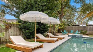 A backyard with a swimming pool, lounge chairs, and a wooden fence. - 1 Mile to Beach Private Pool Oasis Volleyball (Palm Harbor)