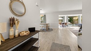 A modern interior with a wooden bench, a round mirror, and a dining area with a table and chairs. - 1 Mile to Beach Private Pool Oasis Volleyball (Palm Harbor)