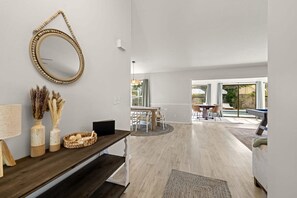 A modern interior with a wooden bench, a round mirror, and a dining area with a table and chairs. - 1 Mile to Beach Private Pool Oasis Volleyball (Palm Harbor)