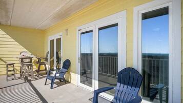 A covered outdoor area with a yellow wall, two sliding glass doors, and a wooden deck.