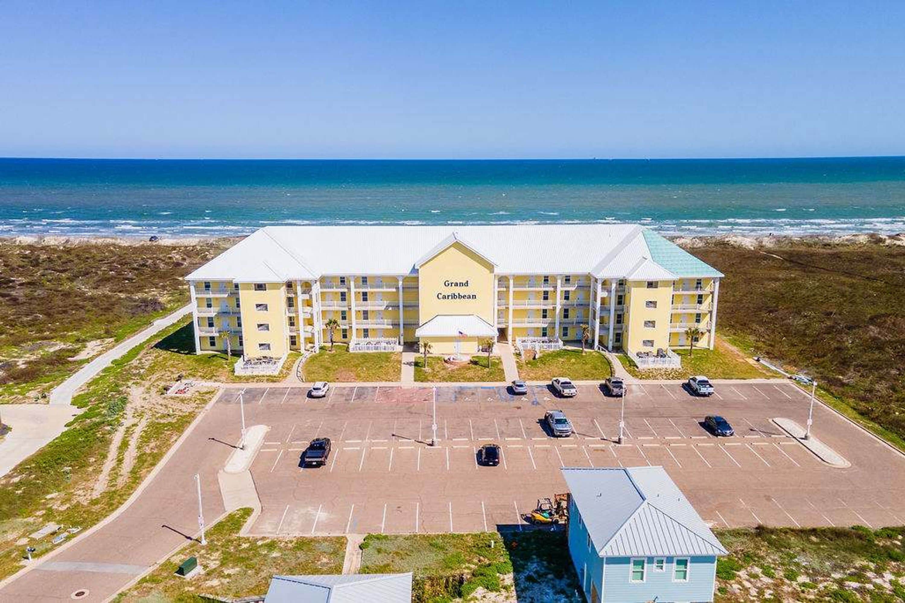 A Grand Caribbean hotel with a parking lot and ocean view.