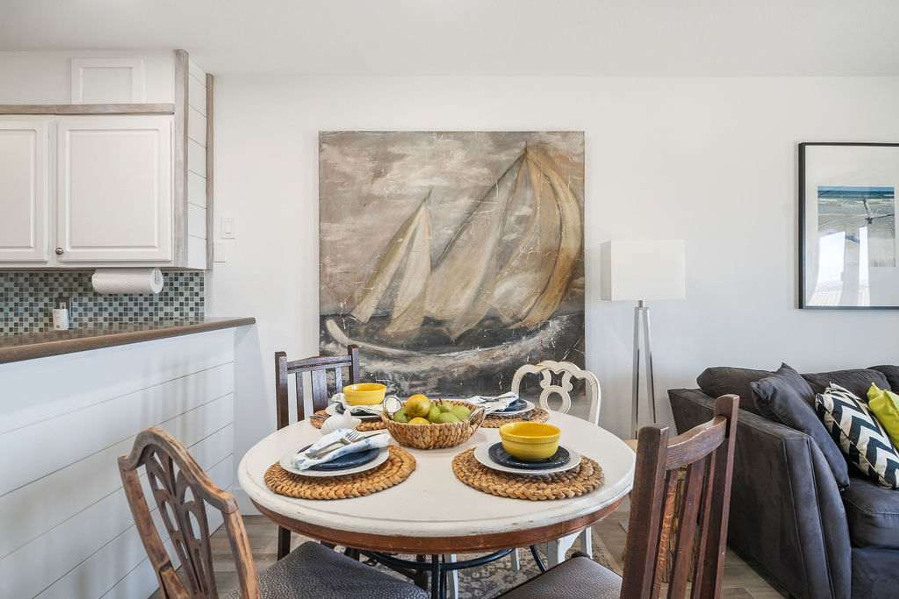 En matplats med ett runt bord, stolar och en målning som föreställer en segelbåt.