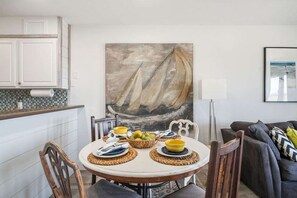 Ein Essbereich mit einem runden Tisch, Stühlen und einem Bild von einem Segelboot.