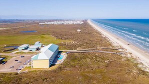 An aerial view of a coastal property with a large building, a parking lot, and a beach. - Ocean Views Boardwalk Access Large Community Pool (Port Aransas)