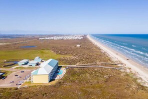 An aerial view of a coastal property with a large building, a parking lot, and a beach. - Ocean Views Boardwalk Access Large Community Pool (Port Aransas)