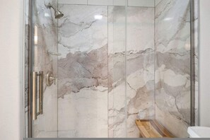 A shower with marble walls and a wooden floor. - Ocean Views Boardwalk Access Large Community Pool (Port Aransas)