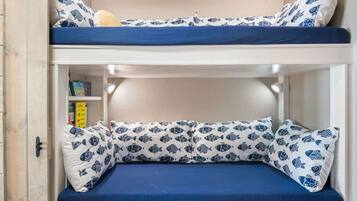 A bunk bed with a lower bunk featuring a shelf with books and a small yellow box.