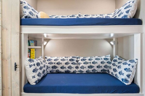 A bunk bed with a lower bunk featuring a shelf with books and a small yellow box.