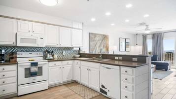 A modern kitchen with white cabinetry, a built-in oven, and a large island with a sink.
