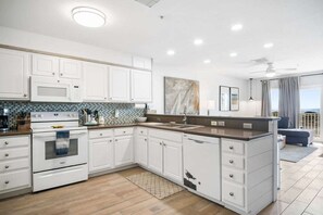 A modern kitchen with white cabinetry, a built-in oven, and a large island with a sink.