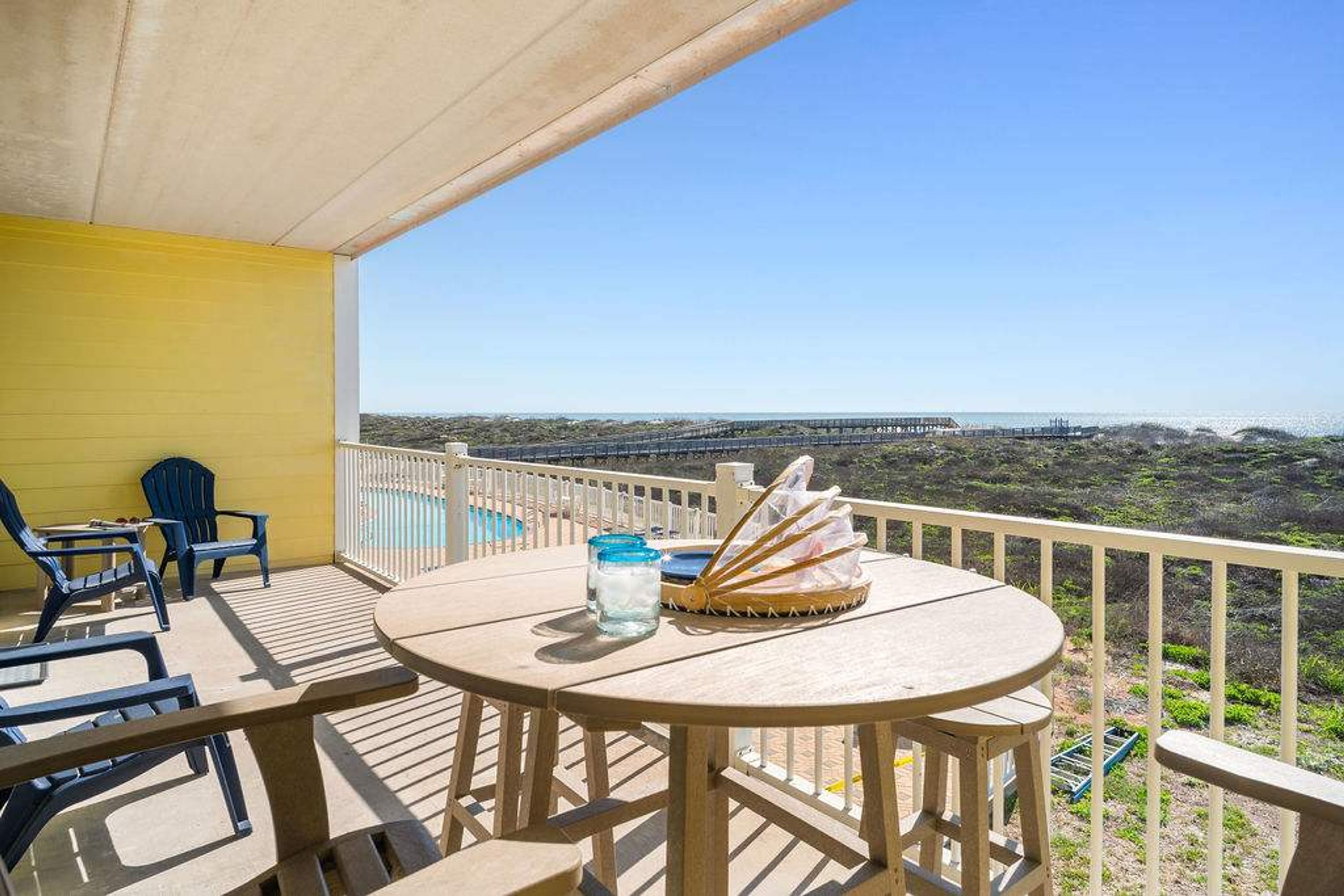 A balcony with a table, chairs, and a view of the ocean.